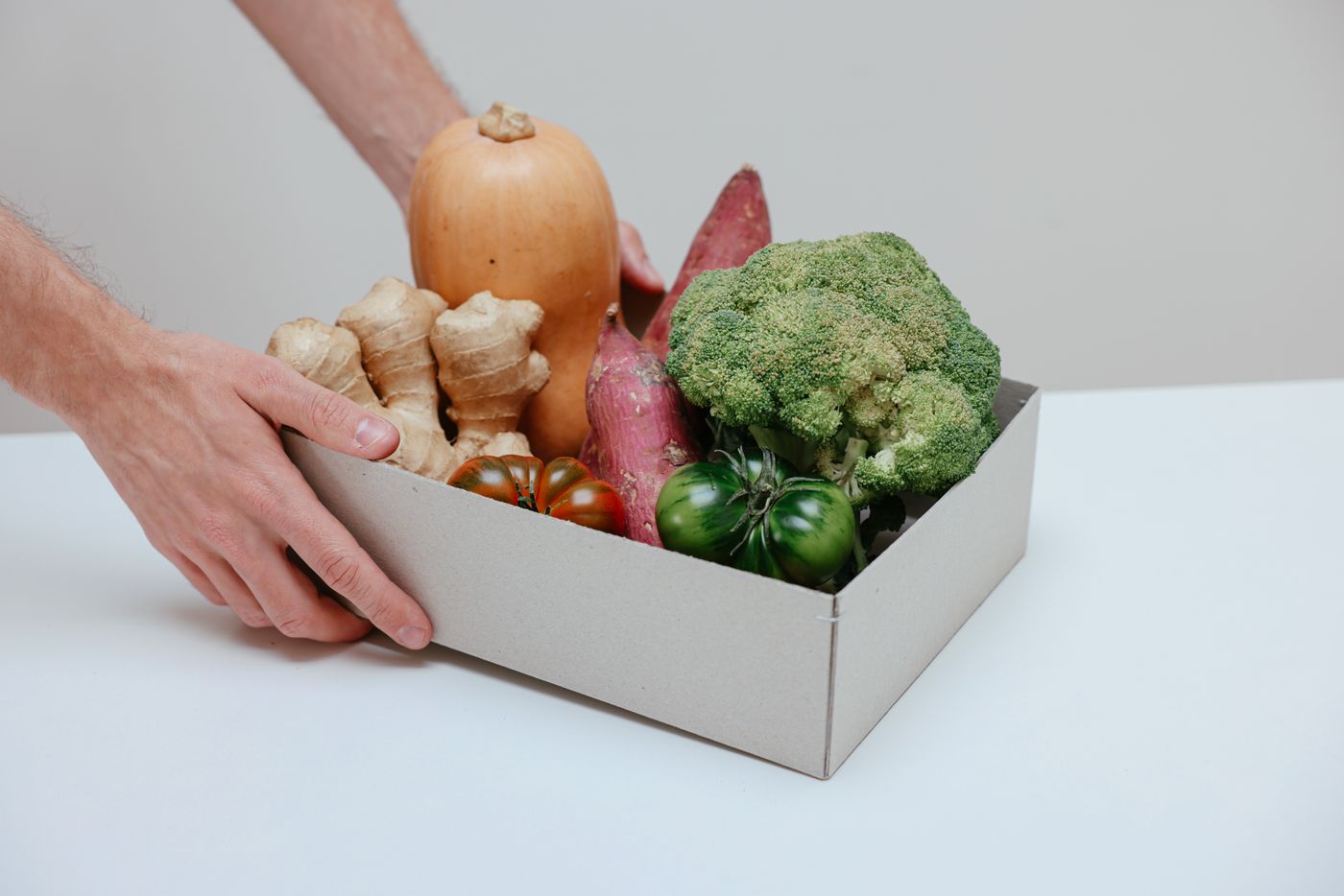 Hands arranging a box of fresh fruits and vegetables